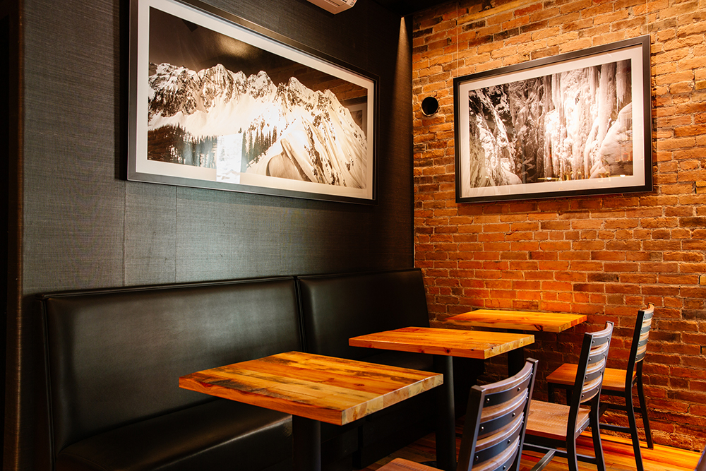 Image of part of the Imogene's whiskey bar seating area, booth seating on one side of the tables and chairs on the the other.